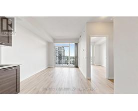 A spacious room with wooden floors and a large window overlooking a cityscape.