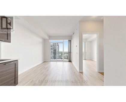 A spacious room with wooden floors and a large window overlooking a cityscape.