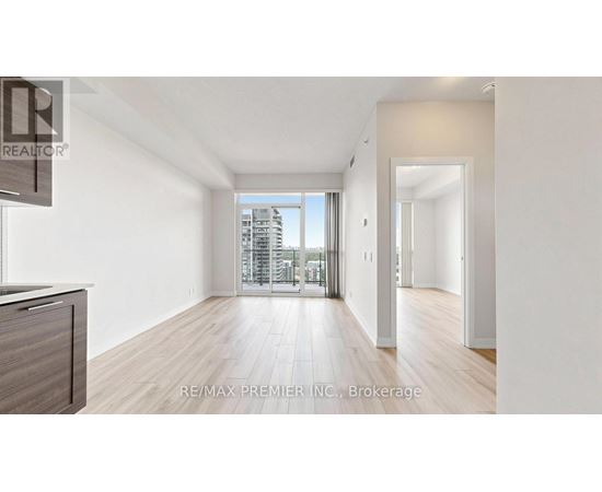 A spacious room with wooden floors and a large window overlooking a cityscape.