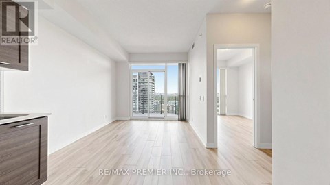 A spacious room with wooden floors and a large window overlooking a cityscape.