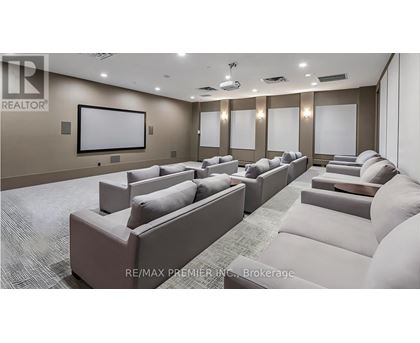 A living room with a row of couches and a large screen on the wall.