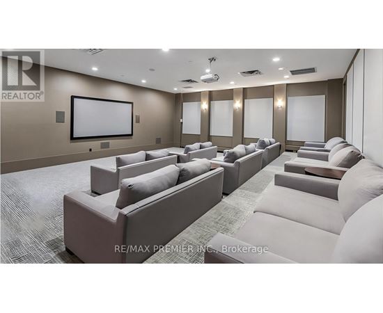 A living room with a row of couches and a large screen on the wall.
