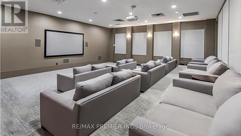 A living room with a row of couches and a large screen on the wall.