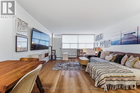 A living room with a wooden table and a couch with a striped blanket on it.