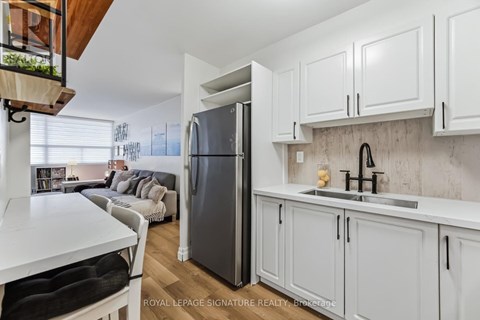 A kitchen with white cabinets and a black fridge.