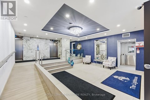 A spacious living room with a staircase and a large mirror.