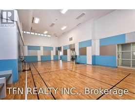 A gym with wooden floors and a sign that says TFN REALTY INC.