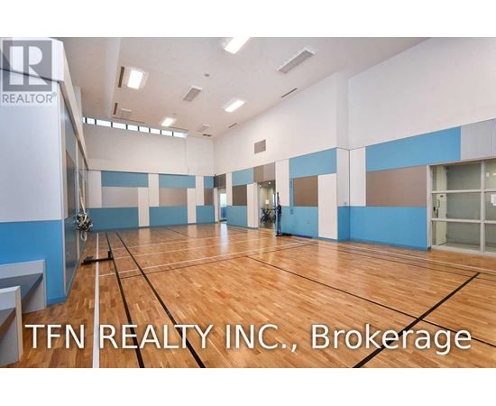 A gym with wooden floors and a sign that says TFN REALTY INC.