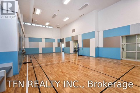 A gym with wooden floors and a sign that says TFN REALTY INC.