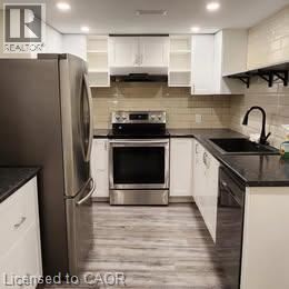 A modern kitchen with a stainless steel refrigerator and white cabinets.