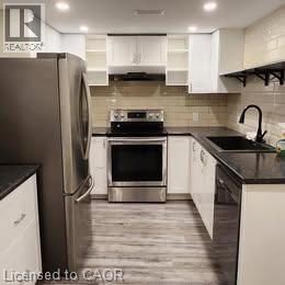 A modern kitchen with a stainless steel refrigerator and white cabinets.