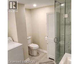 A white toilet sits next to a glass shower door in a bathroom.