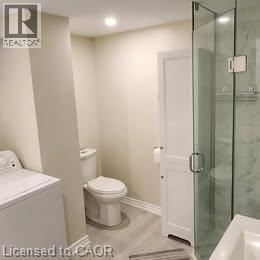 A white toilet sits next to a glass shower door in a bathroom.