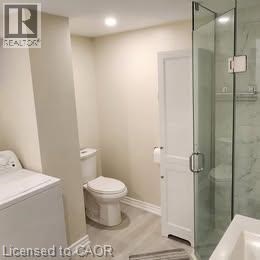 A white toilet sits next to a glass shower door in a bathroom.
