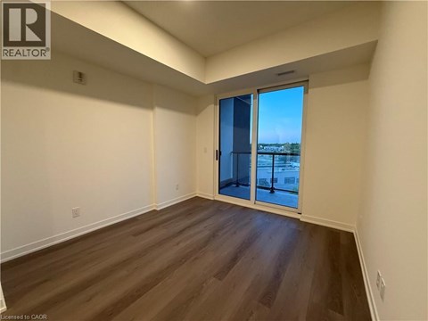 A room with wooden flooring and a sliding glass door leading to a balcony.
