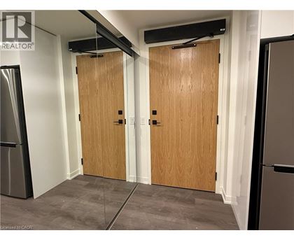 A room with two wooden doors and a refrigerator on the left side.