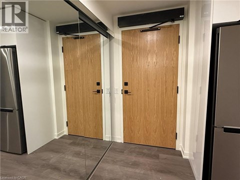 A room with two wooden doors and a refrigerator on the left side.