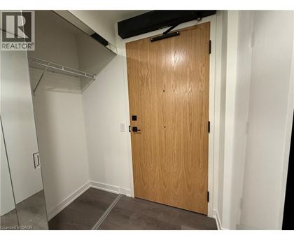 A wooden door in a room with white walls and a grey floor.
