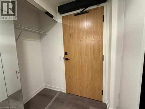 A wooden door in a room with white walls and a grey floor.