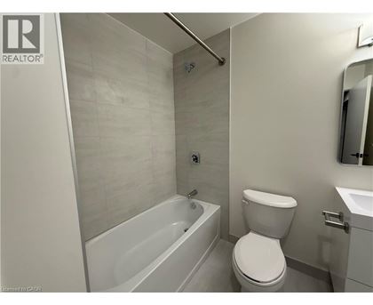 A white toilet is in a bathroom with a white tub and sink.