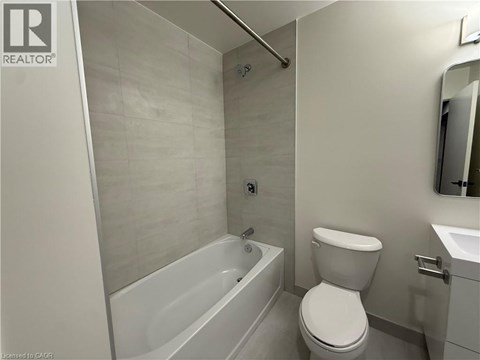 A white toilet is in a bathroom with a white tub and sink.