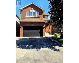 A house with a garage door and a tree in front.