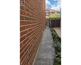 A brick wall with a grey pathway in front of it.