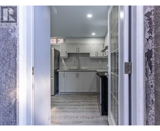 A kitchen with white cabinets and a black refrigerator.