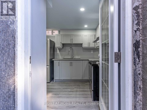 A kitchen with white cabinets and a black refrigerator.