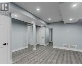 A spacious room with a door on the left and a hallway leading to another room.