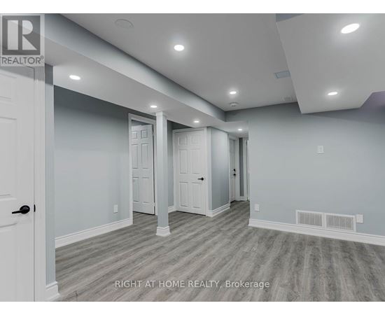 A spacious room with a door on the left and a hallway leading to another room.