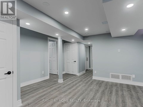 A spacious room with a door on the left and a hallway leading to another room.