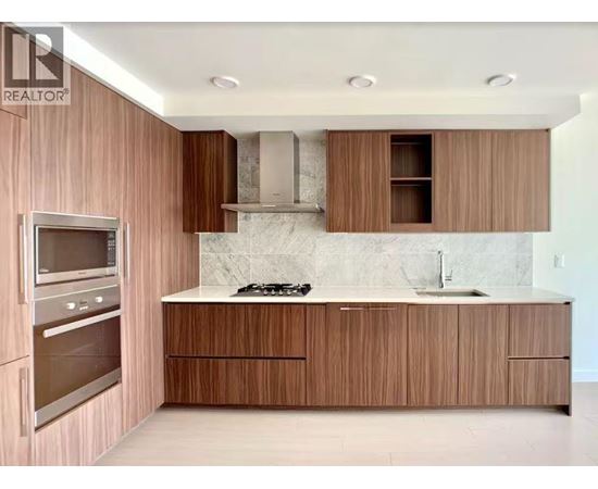 A modern kitchen with wooden cabinets and a marble backsplash.