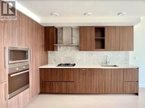 A modern kitchen with wooden cabinets and a marble backsplash.