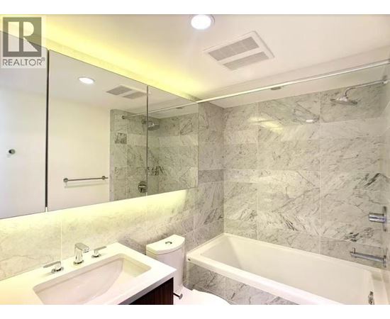 A bathroom with a marble wall and a bathtub.