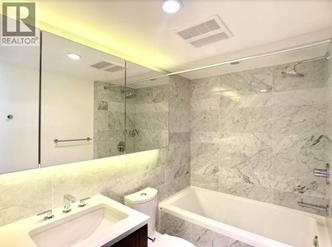 A bathroom with a marble wall and a bathtub.