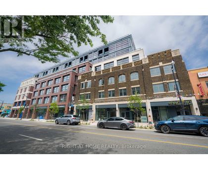 A street view of a multi-story building with cars parked in front.