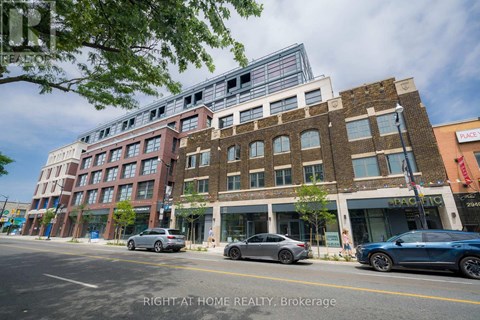 A street view of a multi-story building with cars parked in front.
