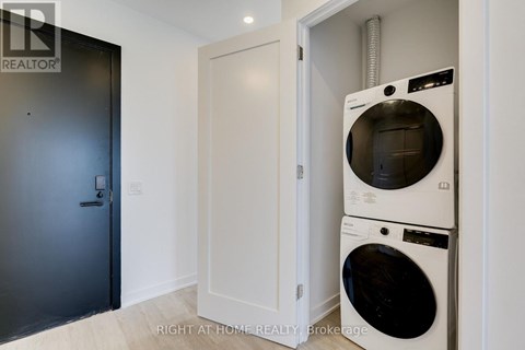 A washing machine is in a small room with a door.