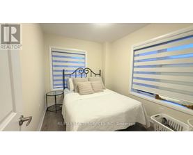 A bedroom with a white bed and a window with blinds.