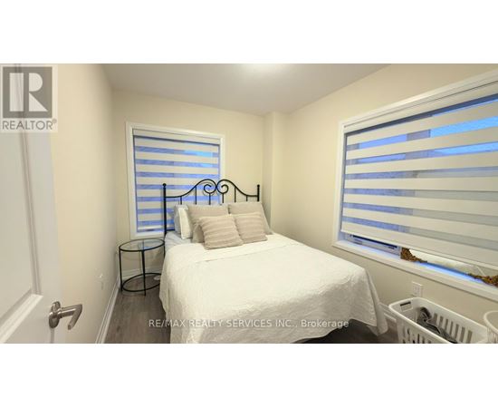 A bedroom with a white bed and a window with blinds.