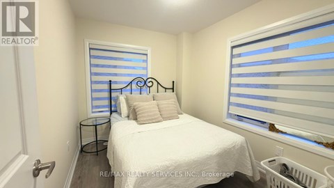 A bedroom with a white bed and a window with blinds.