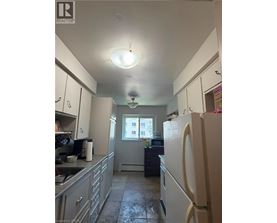 A kitchen with a refrigerator, sink, and cabinets.