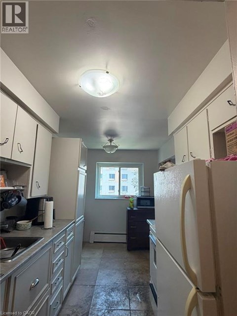 A kitchen with a refrigerator, sink, and cabinets.