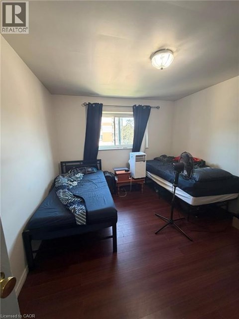 A bedroom with two beds and a window with curtains.