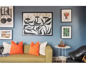 A living room with a green couch, a white table, and framed artwork on the wall.