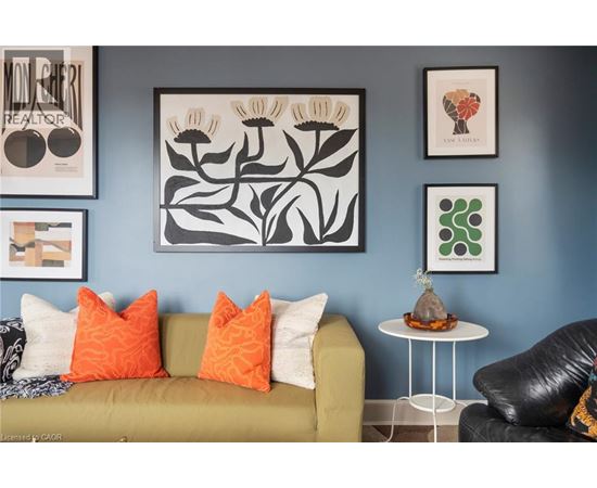 A living room with a green couch, a white table, and framed artwork on the wall.