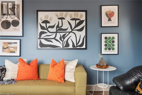 A living room with a green couch, a white table, and framed artwork on the wall.