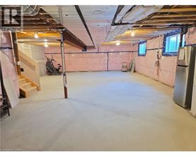 A spacious unfinished room with a staircase and a window.