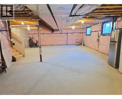 A spacious unfinished room with a staircase and a window.